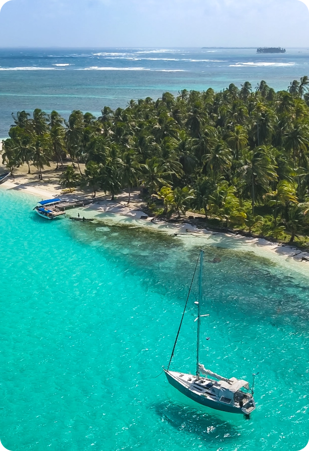Aerial view of Chichime Island in the San Blas Islands, Panama, with a sailboat off the white sandy beach and turquoise waters — a popular destination for San Blas tours from Panama City.
