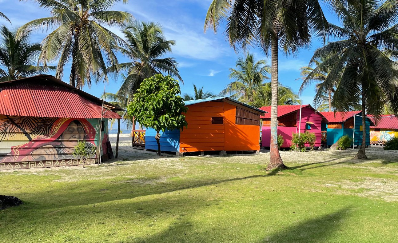 Row of colorful beachfront cabins from behind on Chichime Island, San Blas Islands, Panama – a peaceful island getaway from Panama City.