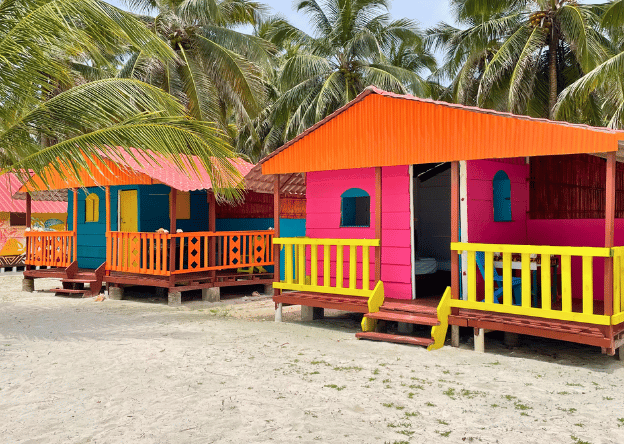 Colorfully painted wooden cabins on Chichime Island, surrounded by white sand and green coconut trees- one of the best accommodations in the San Blas Islands